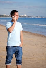 Man_using_phone_on_beach.jpg